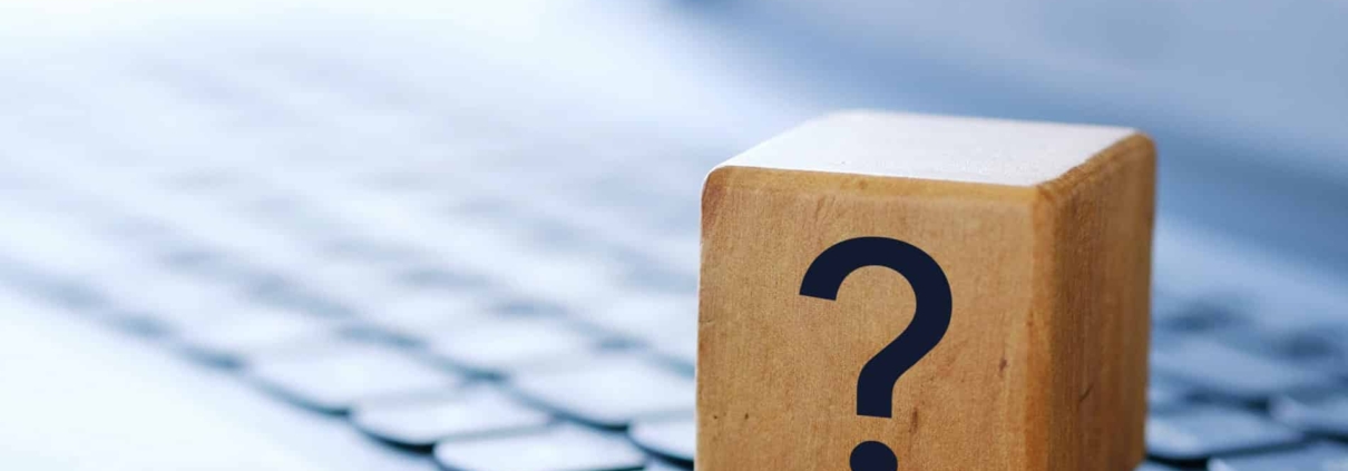 A question mark on a wooden cube on a computer keyboard