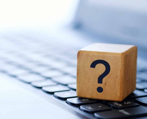 A question mark on a wooden cube on a computer keyboard