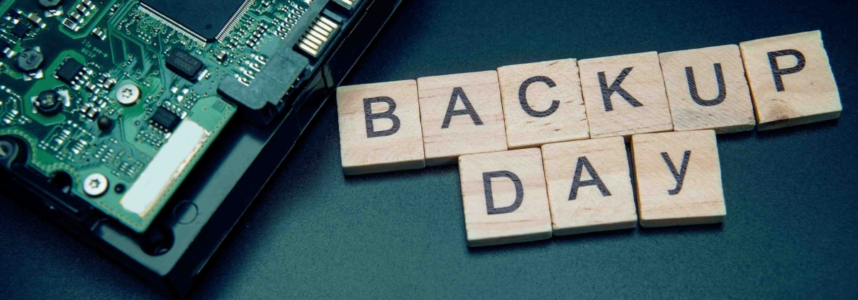 Scrabble Steine formen die Worte "Backup Day" neben Computerplatine